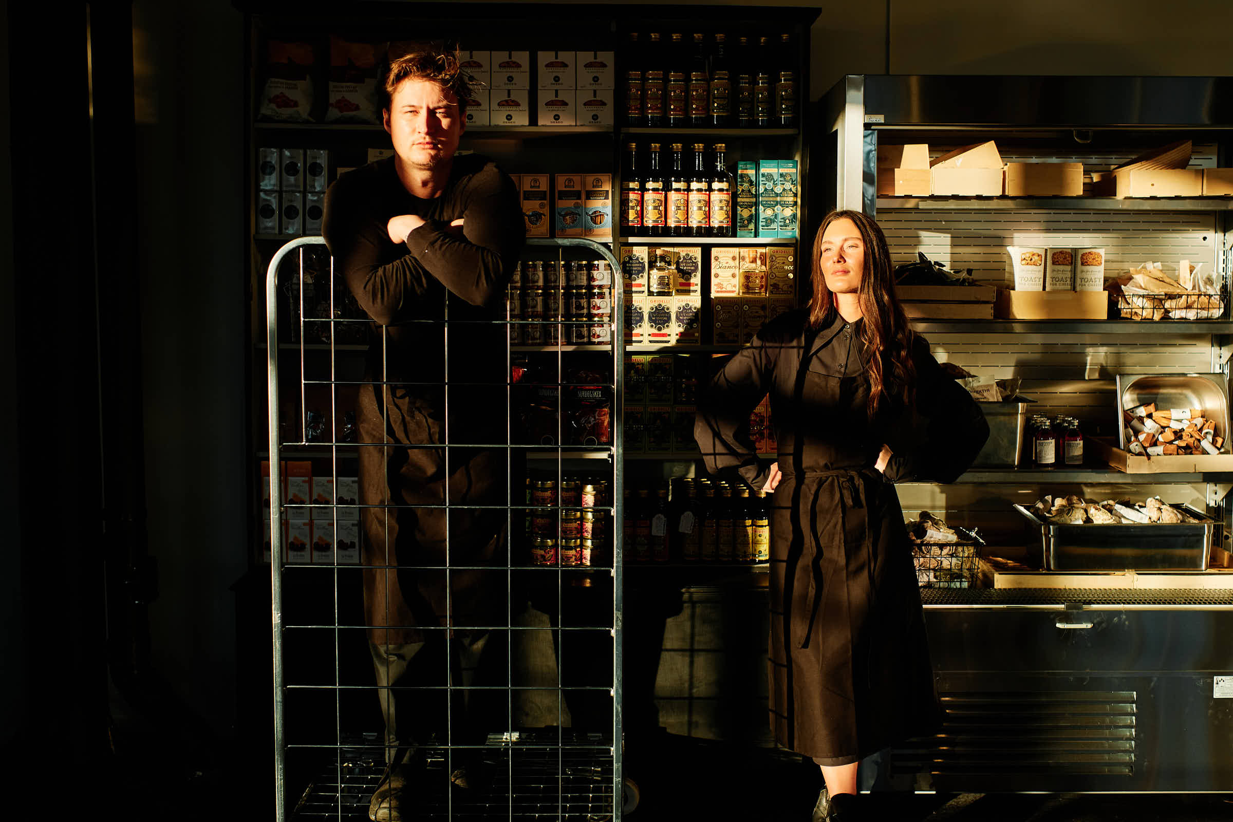 Rasmus and Evelina by the deli shelves at Salt Studio Gävle with provisions and cheese