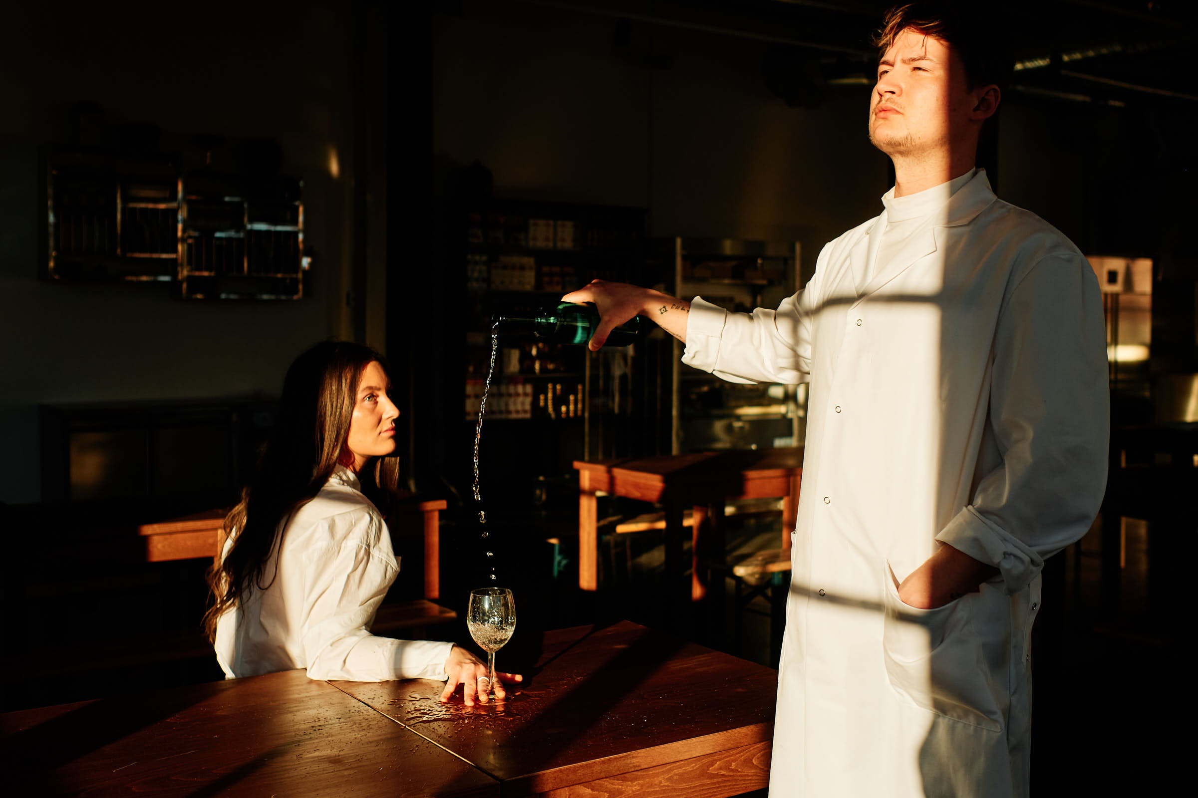 Wine being poured at wooden table inside Salt Studio Gävle restaurant at golden hour